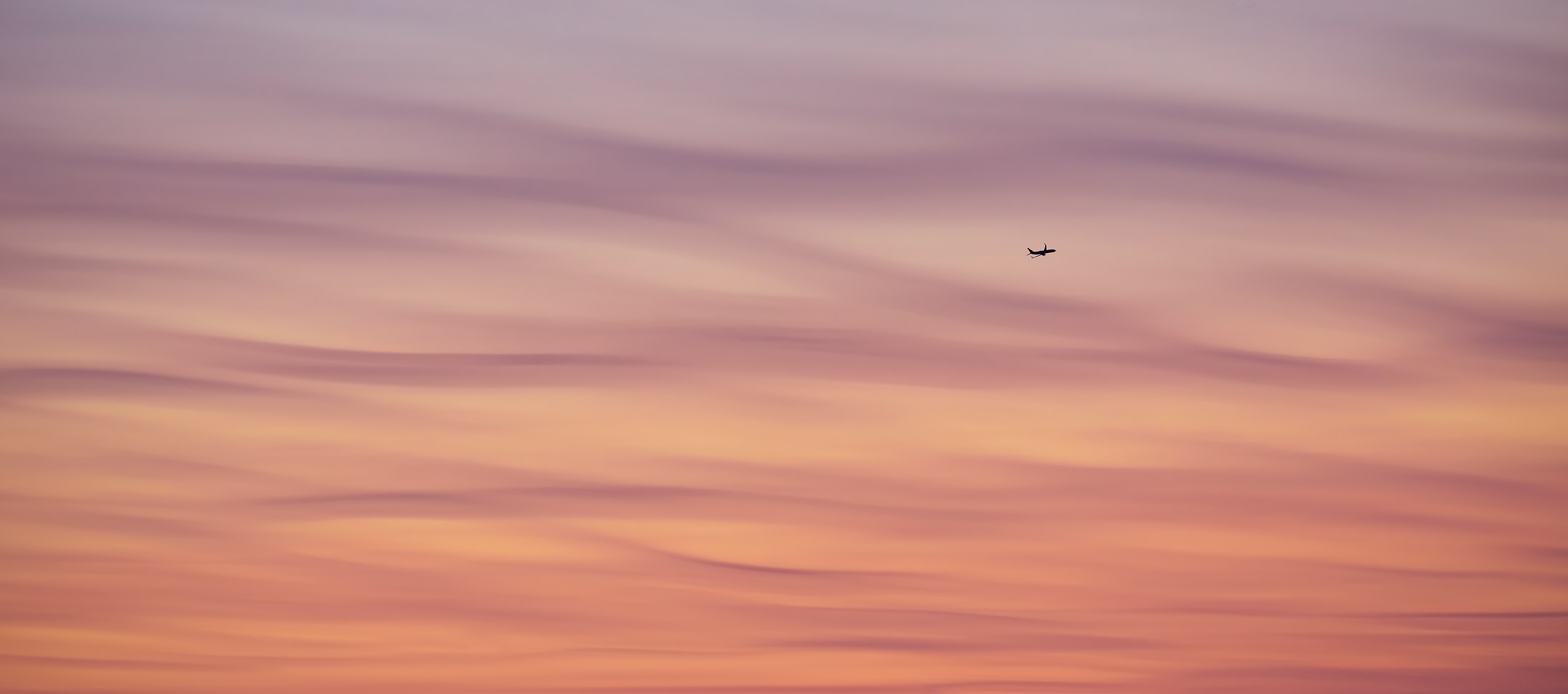 426 megapixels! A very high resolution, large-format VAST photo print of a beautiful sky with wavy, peaceful, and soothing clouds at sunset while an airplane takes off in the distance; artistic photograph created by Dan Piech in New York City.