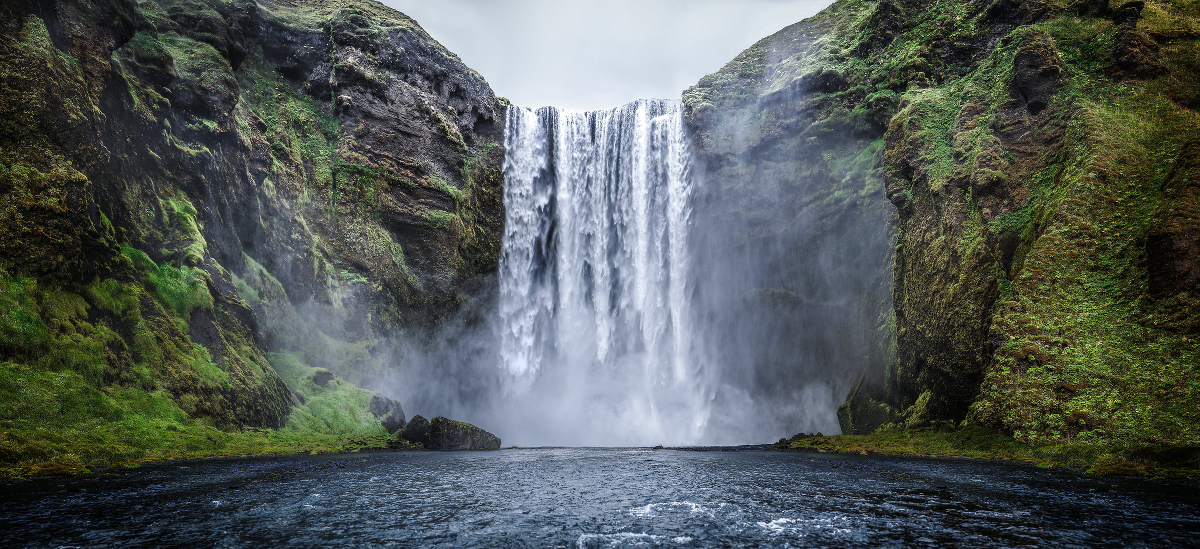 524 megapixels! A very high resolution, large-format VAST photo print of a big waterfall with a river in the foreground and green plants and moss on the sides; photograph created by Dan Piech at the Skógafoss Waterfall in Iceland.