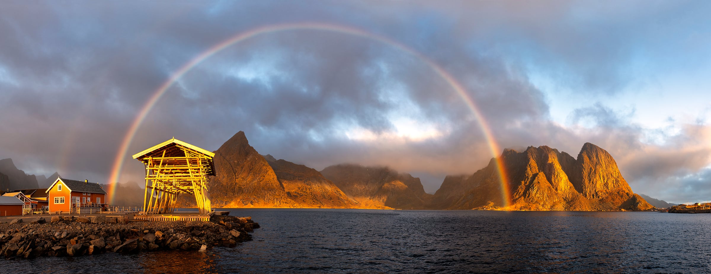 219 megapixels! A very high resolution, large-format VAST photo print of a rainbow over the water and mountains; photograph created by Roberto Moiola in Reine, Lofoten, Norway.