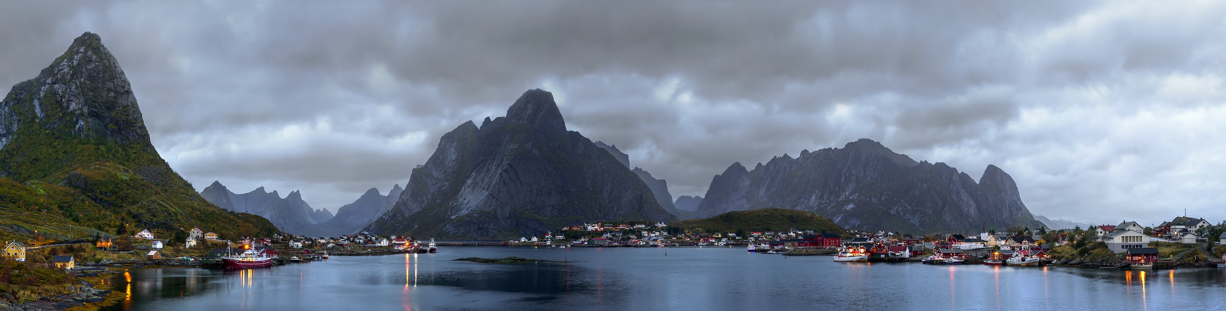 1,701 megapixels! A very high resolution, large-format VAST photo print of a moody landscape with mountains, clouds, a fishing town, and water; photograph created by Ennio Pozzetti in Reine, Lofoten, Norway.