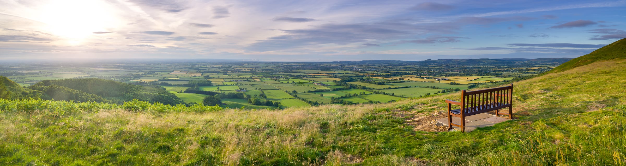 200 megapixels! A very high resolution panorama photo of a heavenly landscape with rural green farmland fields, a sunset, and a peaceful bench; photograph created by Assaf Frank in Yorkshire, Middlesbrough, United Kingdom.