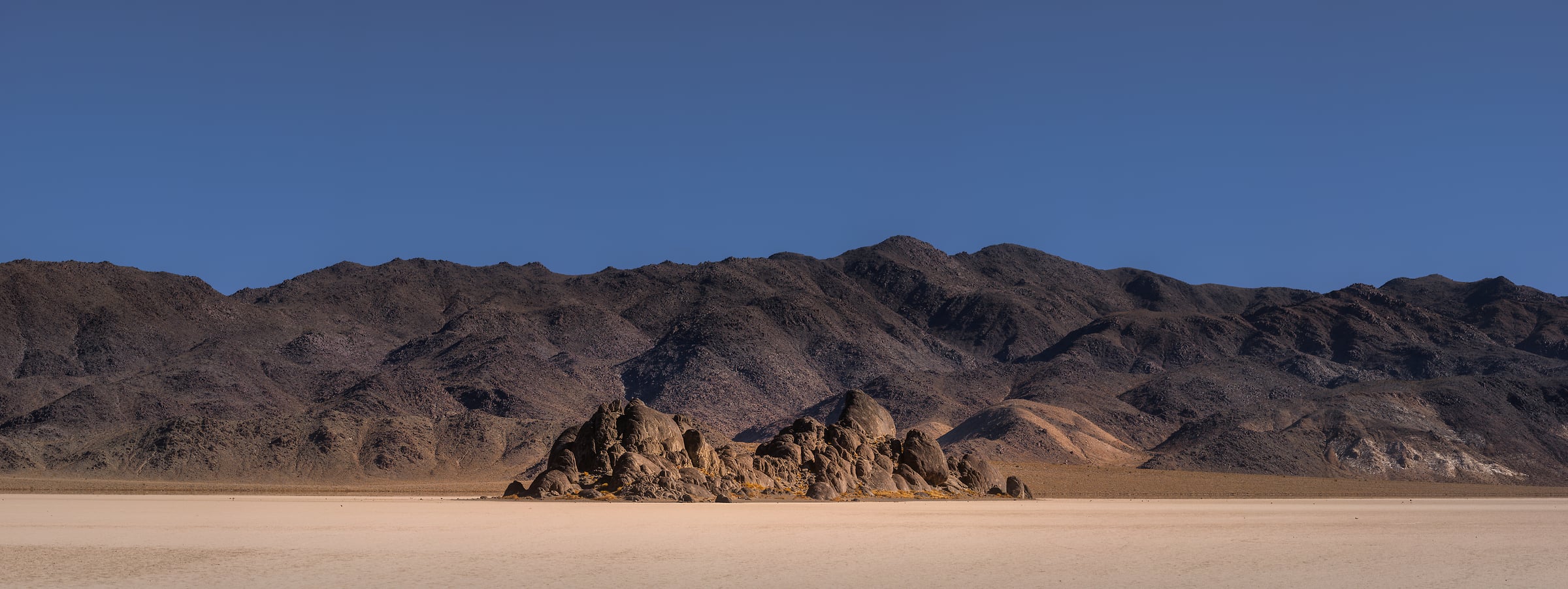 412 megapixels! A very high resolution, large-format VAST photo print of a minimalist landscape scene with a blue sky, some rocky hills, and a desert; landscape photograph created by Chris Blake in Death Valley National Park, California