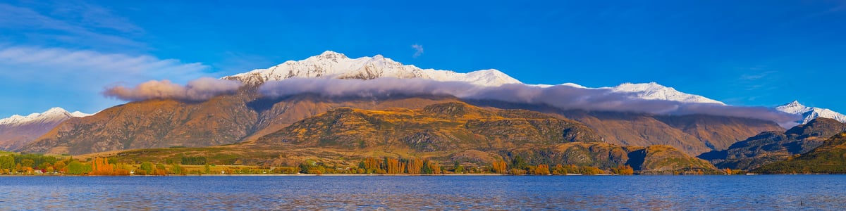 476 megapixels! A very high resolution, panorama photo of an autumn mountain lake perfect for a wall mural with a lake in the foreground, autumn foliage on the mountain in the background, and a snow-covered ridgeline on the mountain; landscape photograph available to be licensed and downloaded; created by John Freeman at Wanaka Lake on South Island, New Zealand.